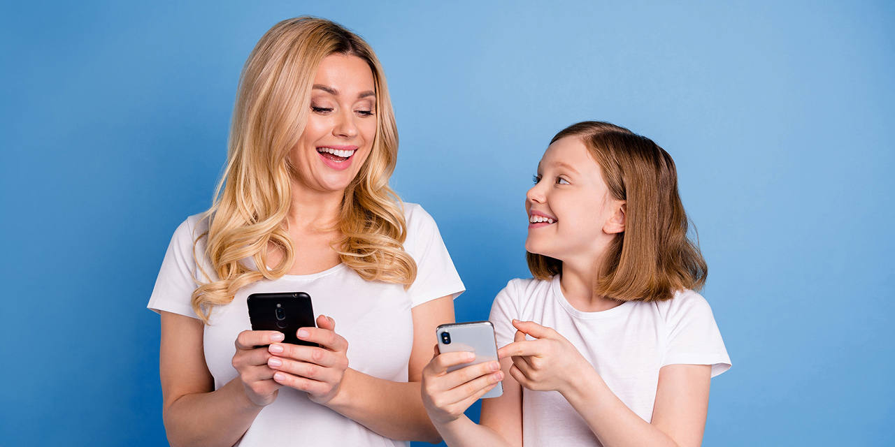 Mutter und Tochter mit Handy in der Hand lachen fröhlich.